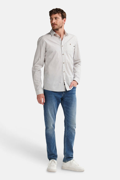 Chemise bleue à manches longues de Petrol Industries, avec un fin motif rayé, portée avec des jeans et des baskets blanches.
