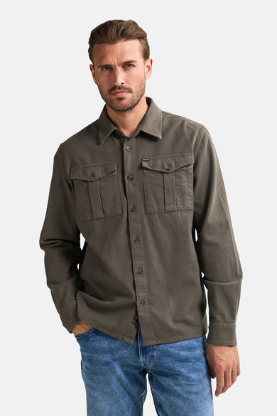 Chemise verte à manches longues de Petrol Industries, avec des poches po po et portée avec un jean bleu.