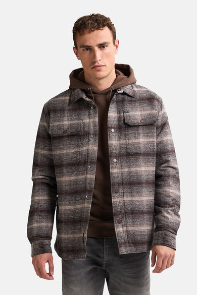 Veste courte brune de Petrol Industries avec un motif à carreaux, portée sur une hoodie brune.