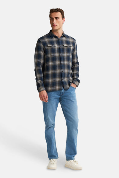 Chemise bleue à carreaux avec des manches longues de Petrol Industries, avec des poches poitrine et portée avec des jeans et des sneakers blanches.