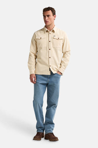 Chemise beige à longues manches de Petrol Industries, avec poches poitrinales et associée à des jeans et des chaussures marron.