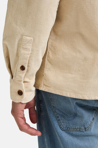 Chemise beige à longues manches de Petrol Industries, détail visible de la texture corduroy et poche arrière en jeans.