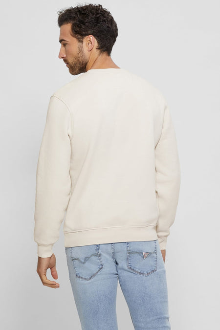 Pull écru Guess® en vue arrière, porté par un homme sur un jean clair avec des poches arrière décorées.