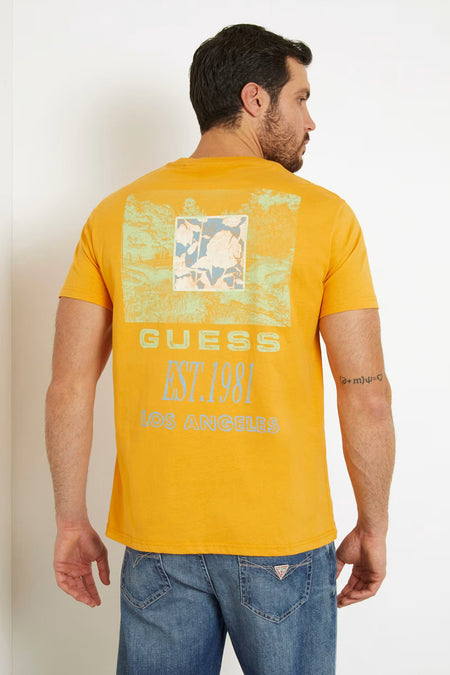 T-shirt orange de Guess avec une imprimé rectangulaire et le texte 'Guess Est. 1981 Los Angeles' sur l'arrière, porté avec des jeans.