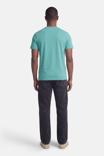 T-shirt vert à manches courtes de Guess, de couleur unie et à coupe décontractée ; à porter avec un jean foncé et des chaussures claires.