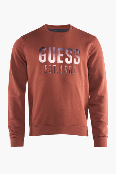 Gilet marron de Guess avec un grand texte "estagé "GUESS EST.1981" sur la partie avant.