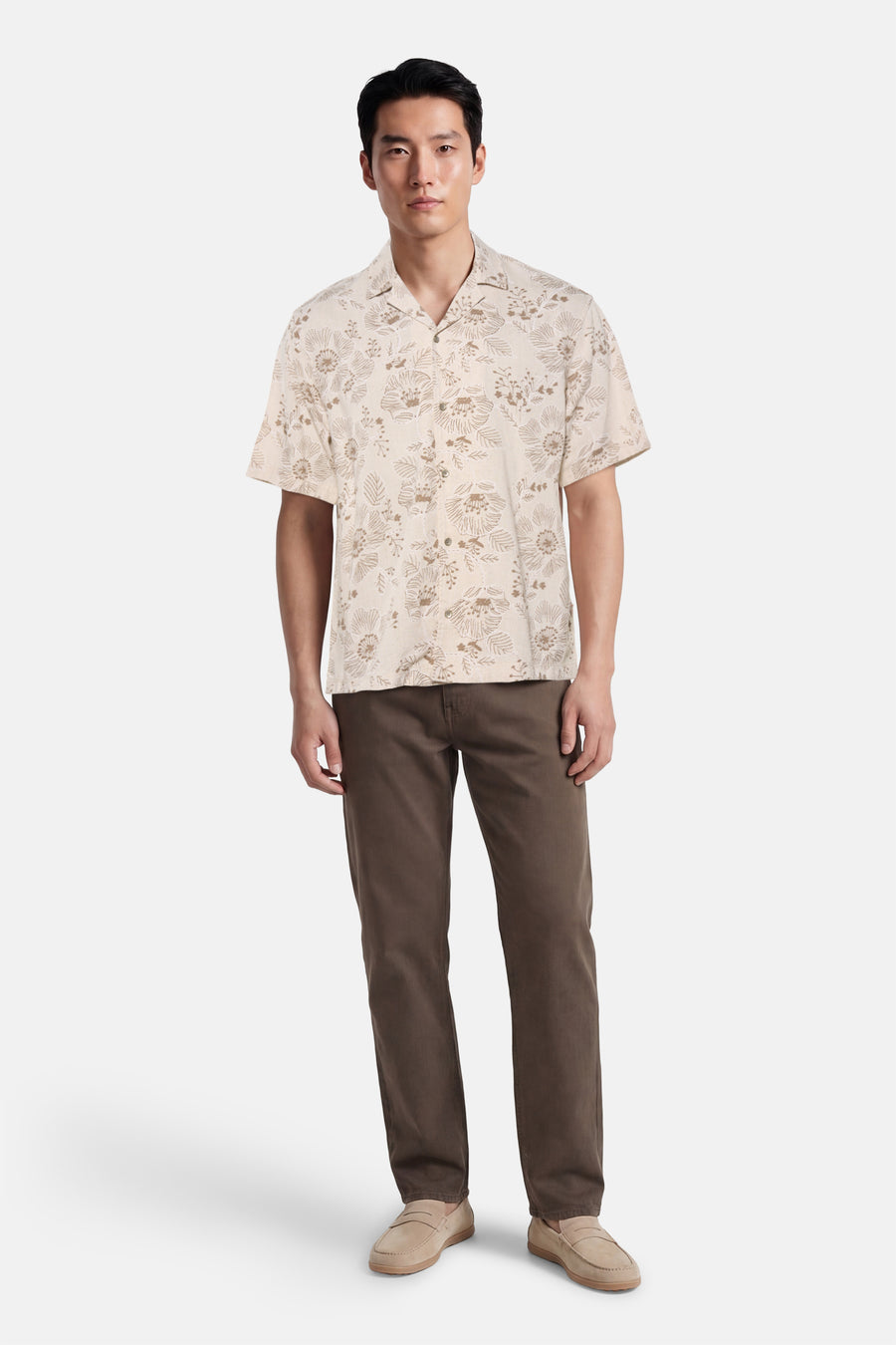 Chemise beige à manches courtes de Guess®, avec un motif floral et assortie à un pantalon et des chaussures marron.