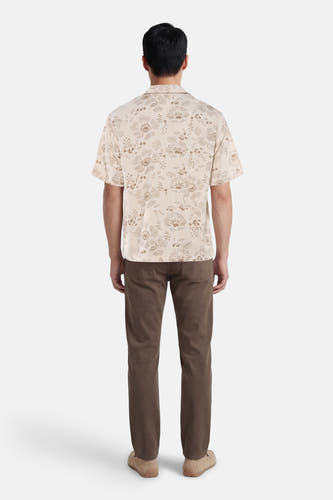 Beige hemd met korte mouwen van Guess®, met een bloemmotief en gecombineerd met bruine broek en schoenen.
