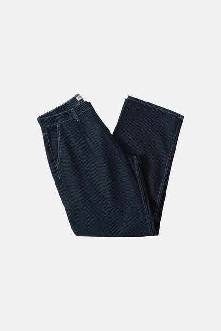 Jean large de denim bleu foncé de Guess, avec des surpiqures blanches et porté avec une ceinture noire.