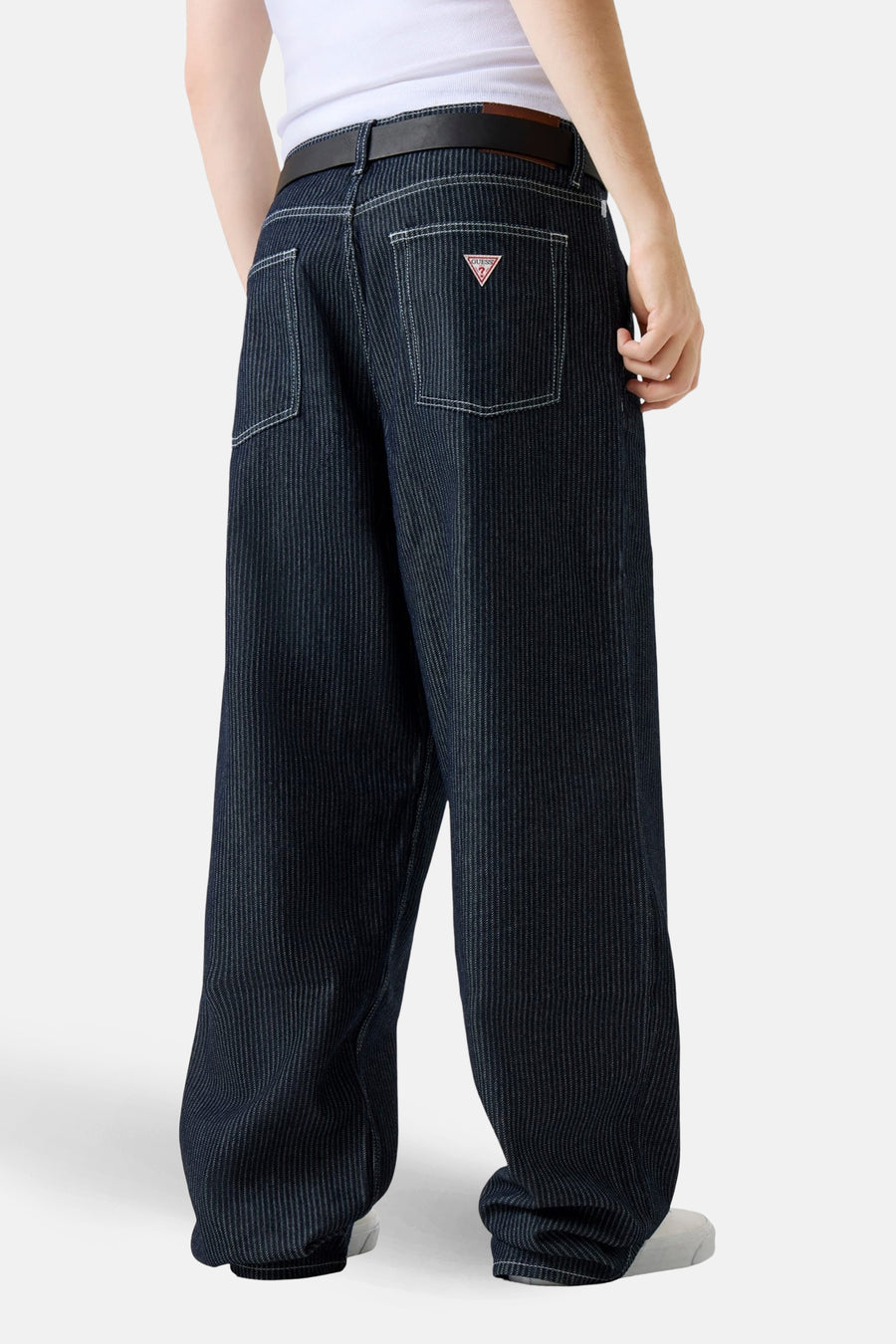 Wijde jeans van donkerblauw denim van Guess, met witte stiksels en gedragen met een zwarte riem.
