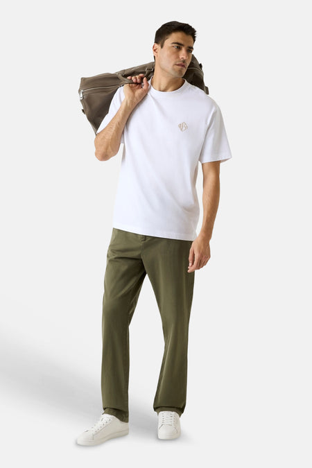 Pantalon vert de Guess à coupe décontractée, porté par un homme avec un t-shirt blanc et des baskets blanches.