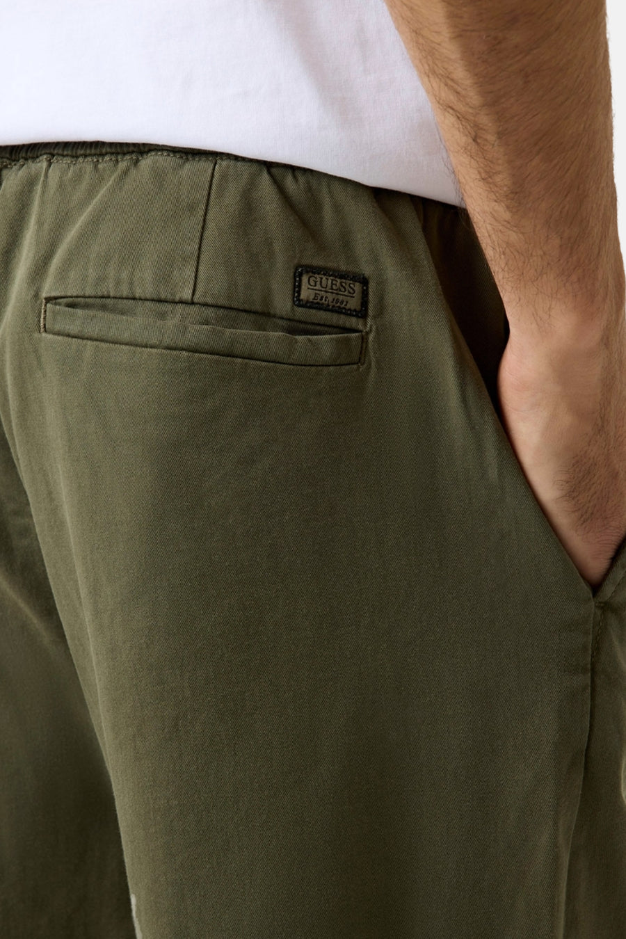 Pantalon vert Guess avec taille élastique, poche arrière avec écusson logo noir et poche pour les mains.