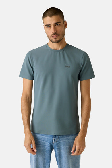 T-shirt bleu à manches courtes de Guess, avec une petite impression sur la poitrine et porté avec un jean.