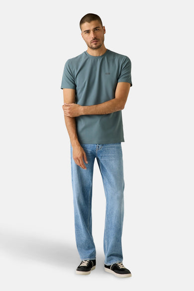 T-shirt bleu à manches courtes de Guess, porté avec un jean décontracté et des baskets noires.