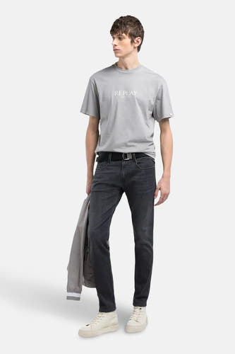Jean slim fit bleu marine de REPLAY, avec une ceinture noire et un T-shirt gris.