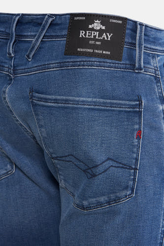 Jean slim fit en denim bleu de Replay, avec poche arrière et détails rouges.