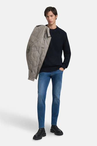 Jean slim en denim bleu moyen de REPLAY, avec un modèle portant une veste sur l'épaule.