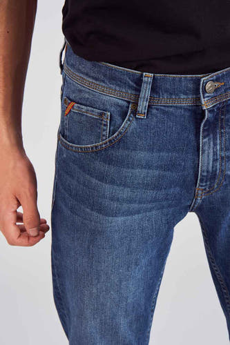 Jean slim fit bleu de Le Fabuleux Marcel de Bruxelles, porté dans un cadre de vie avec une chemise rayée et des baskets.