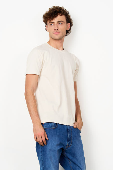 Ecru T-shirt van Le Fabuleux Marcel de Bruxelles, met korte, opgerolde mouwen en ronde hals, gedragen door een man.