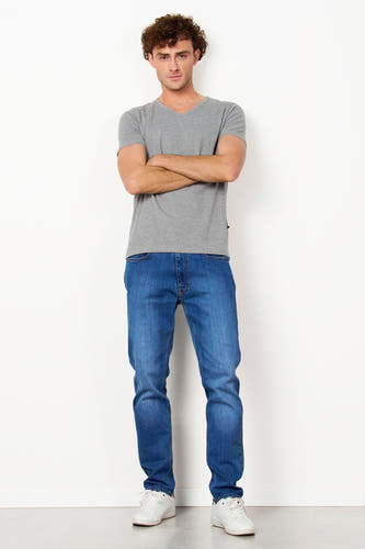 T-shirt gris de Le Fabuleux Marcel de Bruxelles, à manches courtes, associé à des jeans foncés et des baskets blanches.