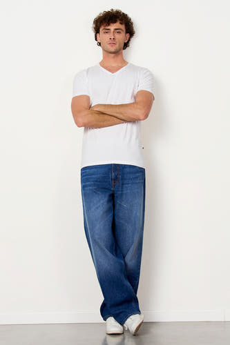 T-shirt blanc de Le Fabuleux Marcel de Bruxelles, porté avec des jeans foncés et des baskets blanches.
