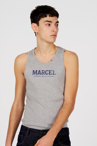 Grijze tanktop van Le Fabuleux Marcel de Bruxelles, met blauwe print en ribstructuur, gedragen met een donkere jeans.
