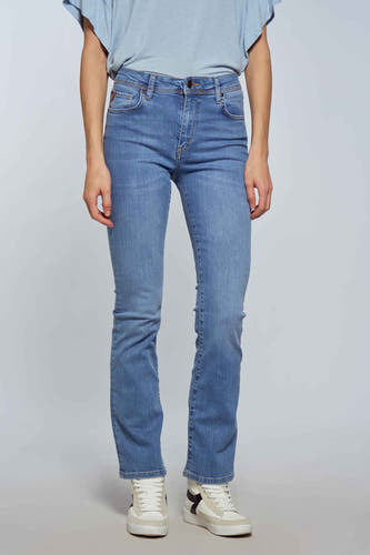 Jean bootcut en denim bleu clair de Le Fabuleux Marcel de Bruxelles, avec un style décontracté et des baskets blanches.