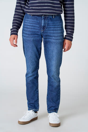 Jean denim bleu moyen 7/8 de Le Fabuleux Marcel de Bruxelles, avec une texture stonewashed et des baskets blanches.