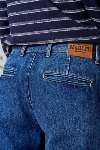 7/8 jeans en denim bleu, de Le Fabuleux Marcel de Bruxelles, avec des poches arrière et des passants, associés à une chemise rayée.