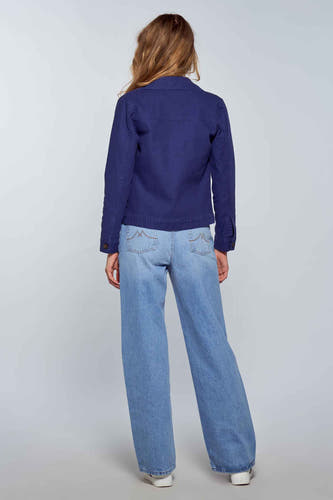 Jean bleu clair large de Le Fabuleux Marcel de Bruxelles, associé à une veste bleue et des baskets blanches.