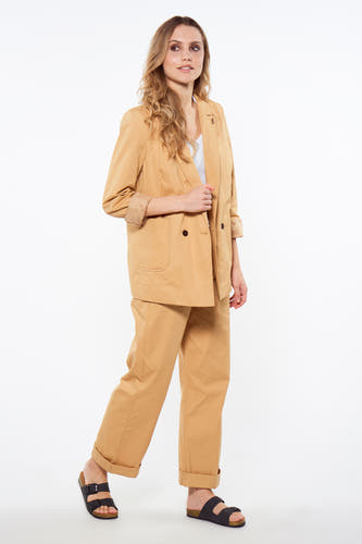 Blazer marron de Le Fabuleux Marcel de Bruxelles, avec manches longues, porté avec un chemisier blanc et un pantalon marron.