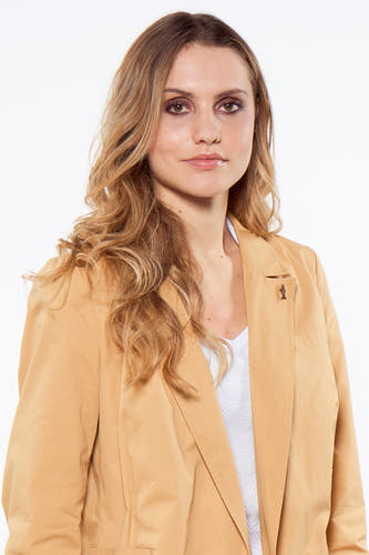 Blazer marron de Le Fabuleux Marcel de Bruxelles, avec une petite broche et porté sur un haut blanc.