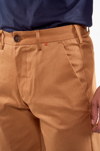 Pantalon de costume brun du Le Fabuleux Marcel de Bruxelles, avec une subtile texture verticale et une petite bande rouge et blanche.
