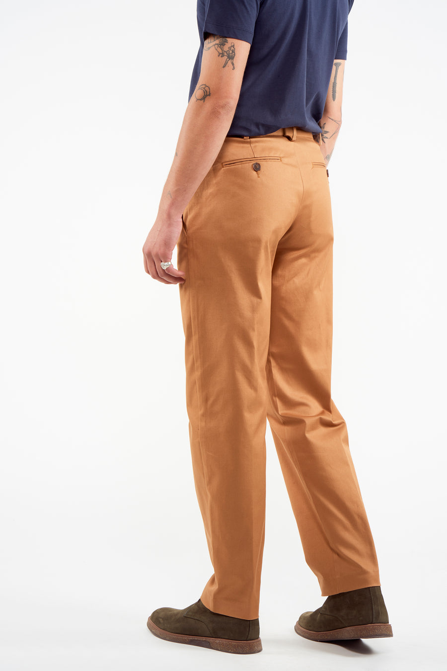 Pantalon de costume brun du Le Fabuleux Marcel de Bruxelles, vu de derrière, associé à un T-shirt bleu foncé et des chaussures en cuir de mouton.
