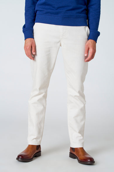 Pantalon blanc de Le Fabuleux Marcel de Bruxelles, vu de derrière, avec des chaussures marrons et un pull bleu.