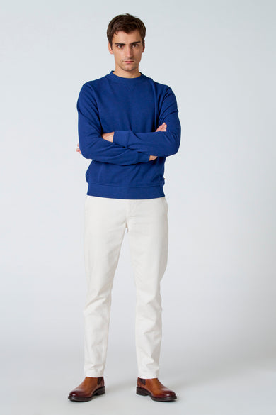 Pantalon blanc de Le Fabuleux Marcel de Bruxelles, associé à une chemise bleue et des bottes en cuir marron.