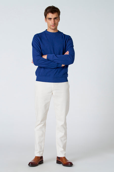 Pantalon blanc de Le Fabuleux Marcel de Bruxelles, associé à une chemise bleue et des bottes en cuir marron.