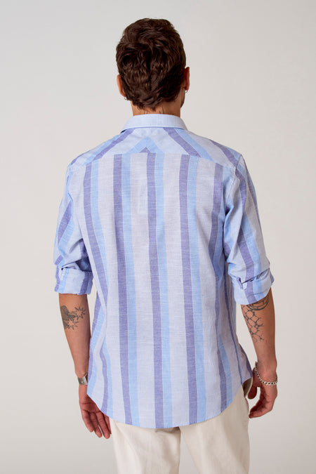 Chemise rayée bleue de Le Fabuleux Marcel de Bruxelles, vue arrière avec des manches roulées et des tatouages.