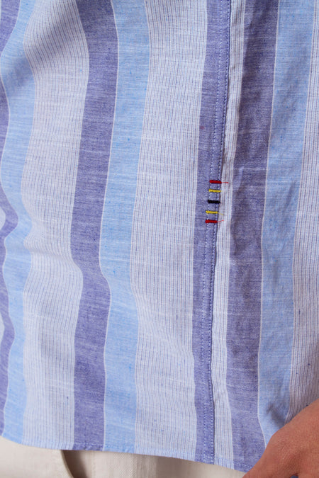 Chemise bleue à rayures courtes de Marcel de Le Fabuleux de Bruxelles, avec des broderies colorées sur la couture.