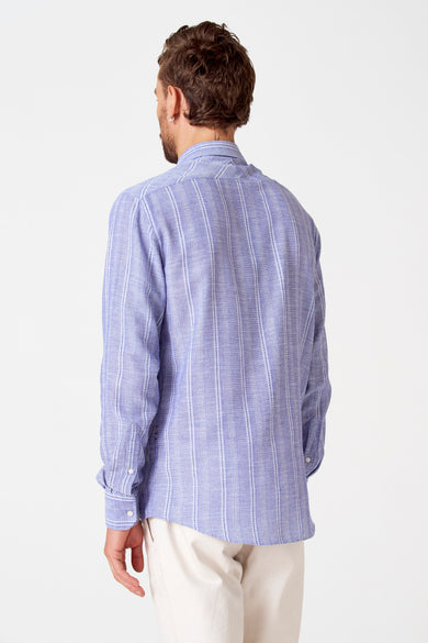 Chemise rayée bleue de Le Fabuleux Marcel de Bruxelles, vue de derrière, avec des manches longues et un short blanc.