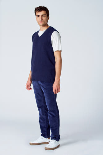 T-shirt bleu de Le Fabuleux Marcel de Bruxelles, porté sur un chemisier rayé et un pantalon en corduroy, avec des baskets blanches.