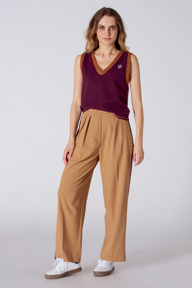 Débardeur bordeaux avec col en V et bordure brune, de Le Fabuleux Marcel de Bruxelles, porté avec un pantalon large beige et des baskets blanches, vue de face.