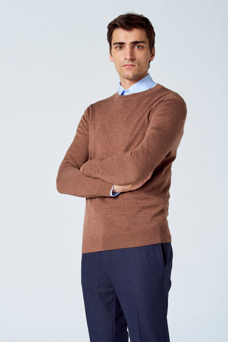 Pull marron avec col rond de Le Fabuleux Marcel de Bruxelles, porté sur une chemise bleu clair, avec un pantalon bleu marine.