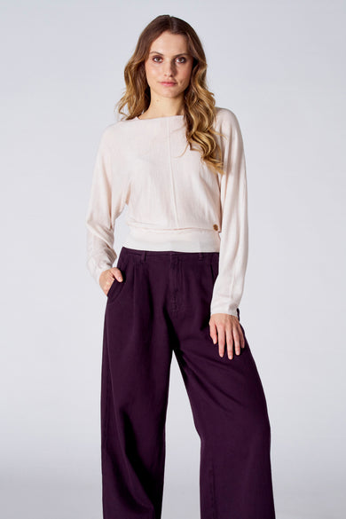 Pull blanc à col rond de Le Fabuleux Marcel de Bruxelles, associé à un pantalon large et fluide violet.