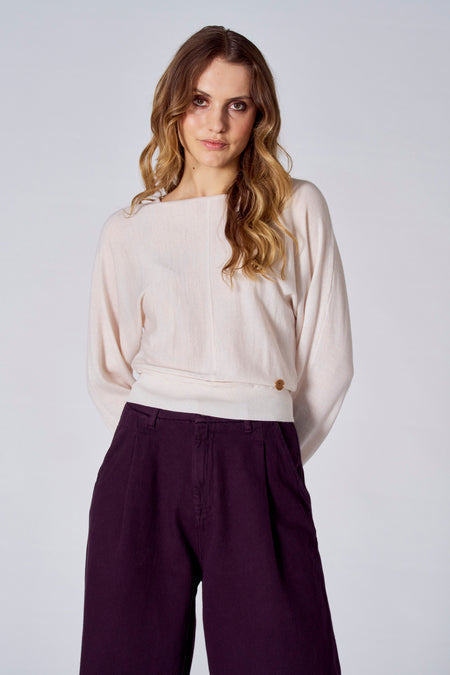 Pull blanc avec col rond de Le Fabuleux Marcel de Bruxelles, porté avec un pantalon violet.
