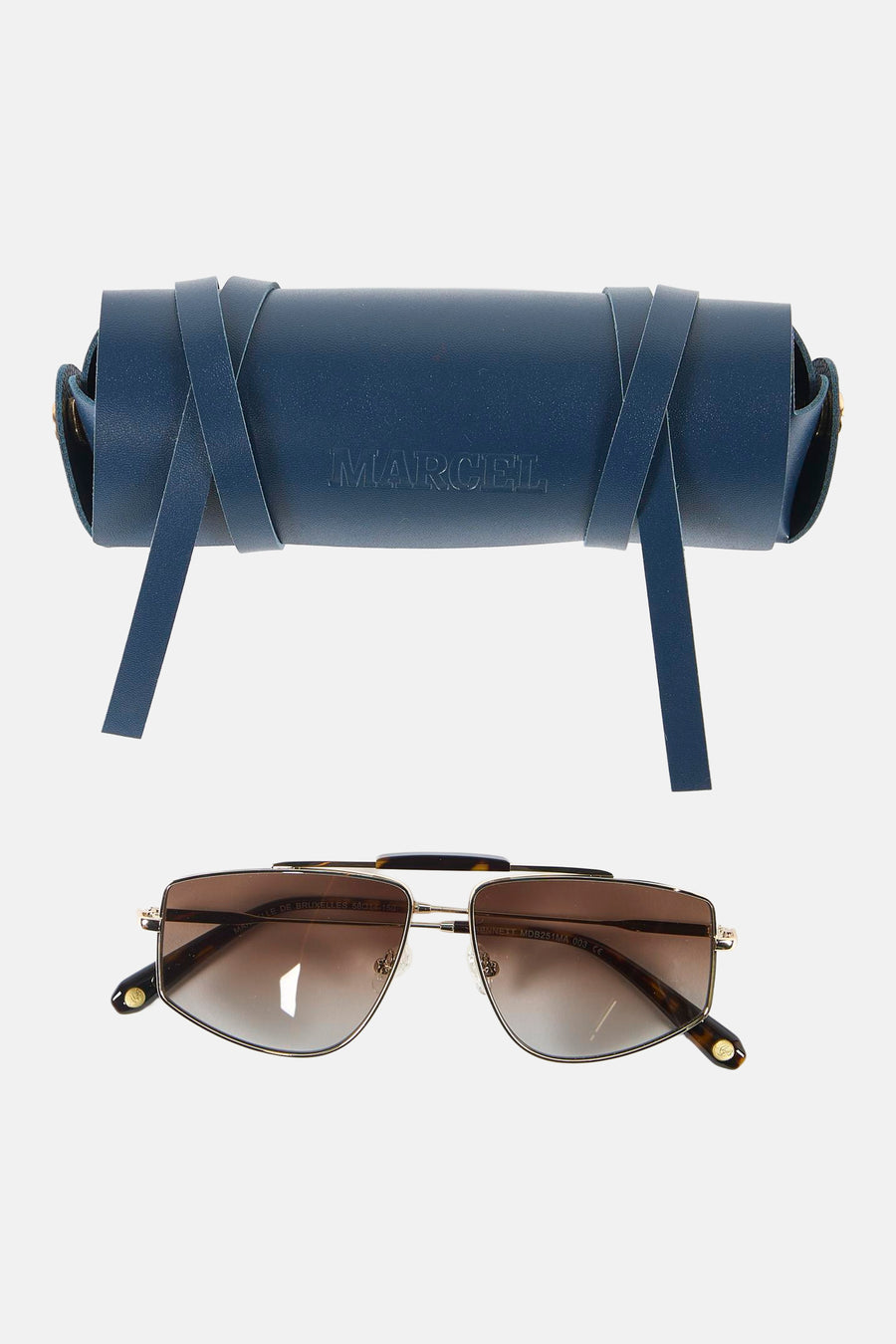 Lunettes de soleil dorées de Le Fabuleux Marcel de Bruxelles avec verres marron, posées devant un étui de rangement en cuir bleu foncé.