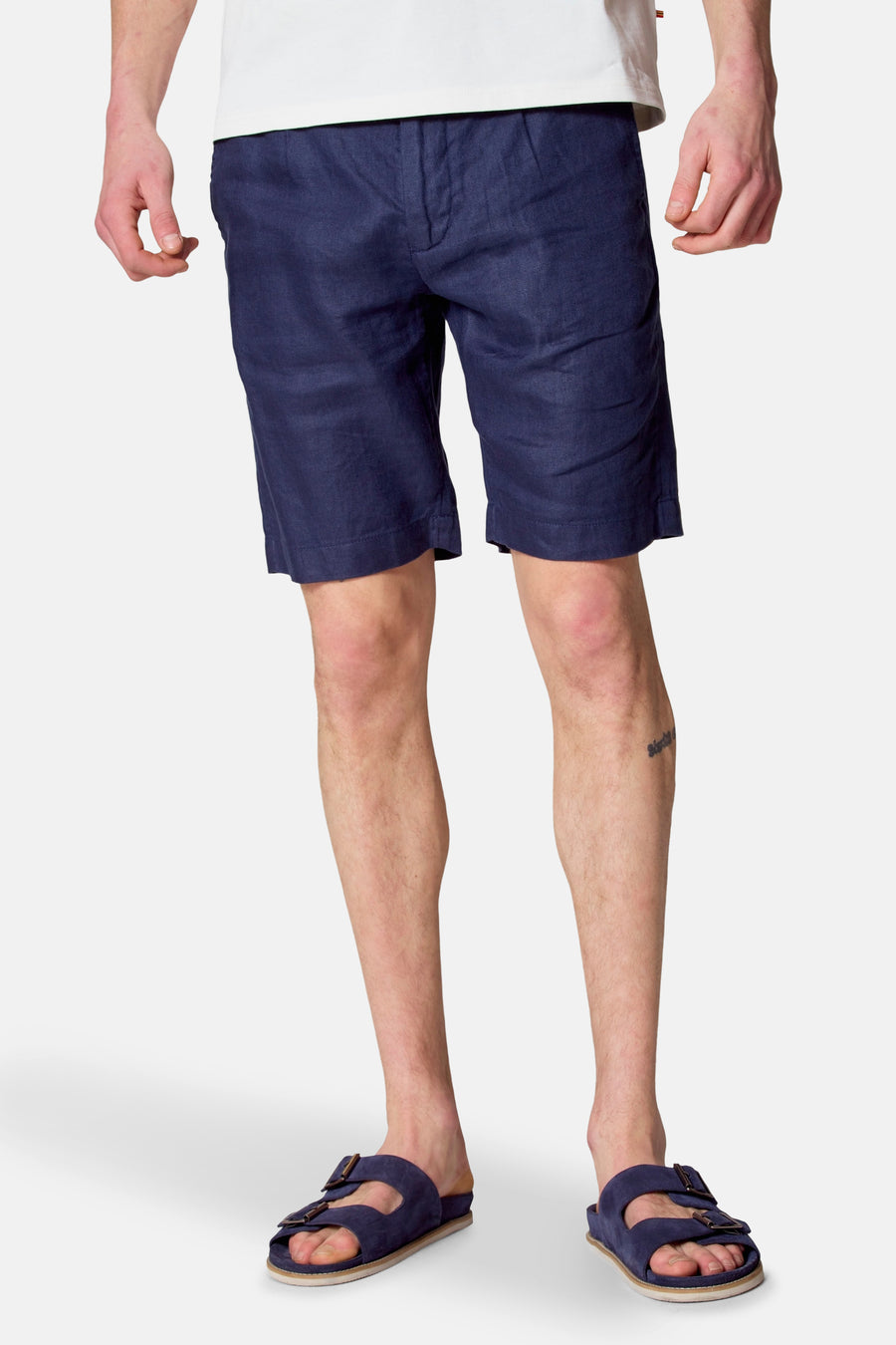 Staande man in blauwe linnen shorts en sandalen.