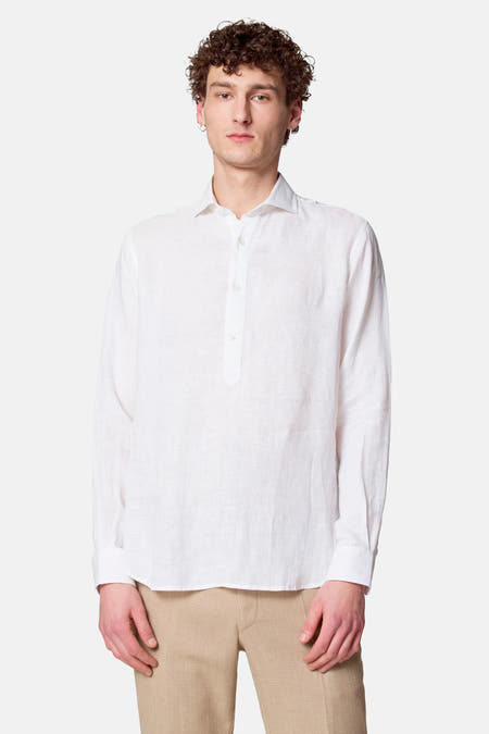 Blouse blanche à manches longues de Le Fabuleux Marcel de Bruxelles, portée avec un pantalon marron.