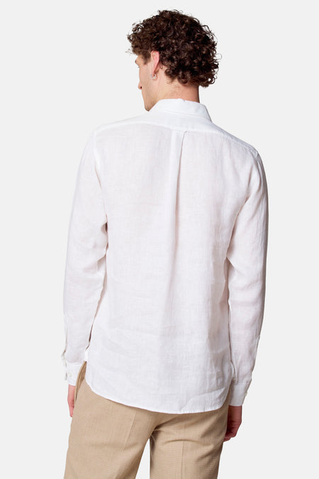 Achterkant van een man met een wit linnen overhemd en beige broek.
