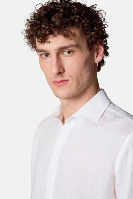 Man met krullend haar en wit linnen overhemd.
